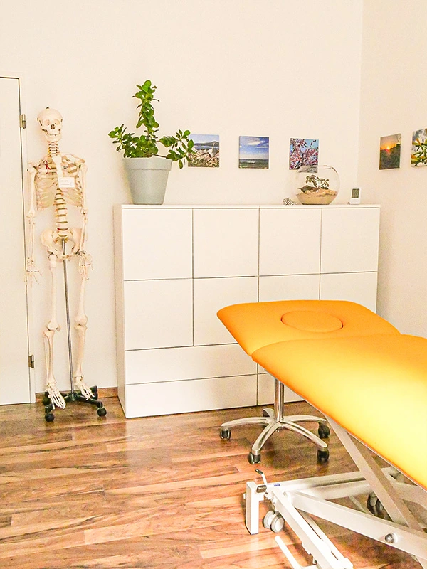 Gelbe gemütliche Liege und weißes Regal im Osteopathie Praxisraum von Christine Schreiber in Aachen